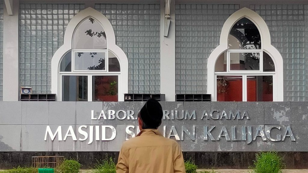 Man in front of a building with arabic writing.